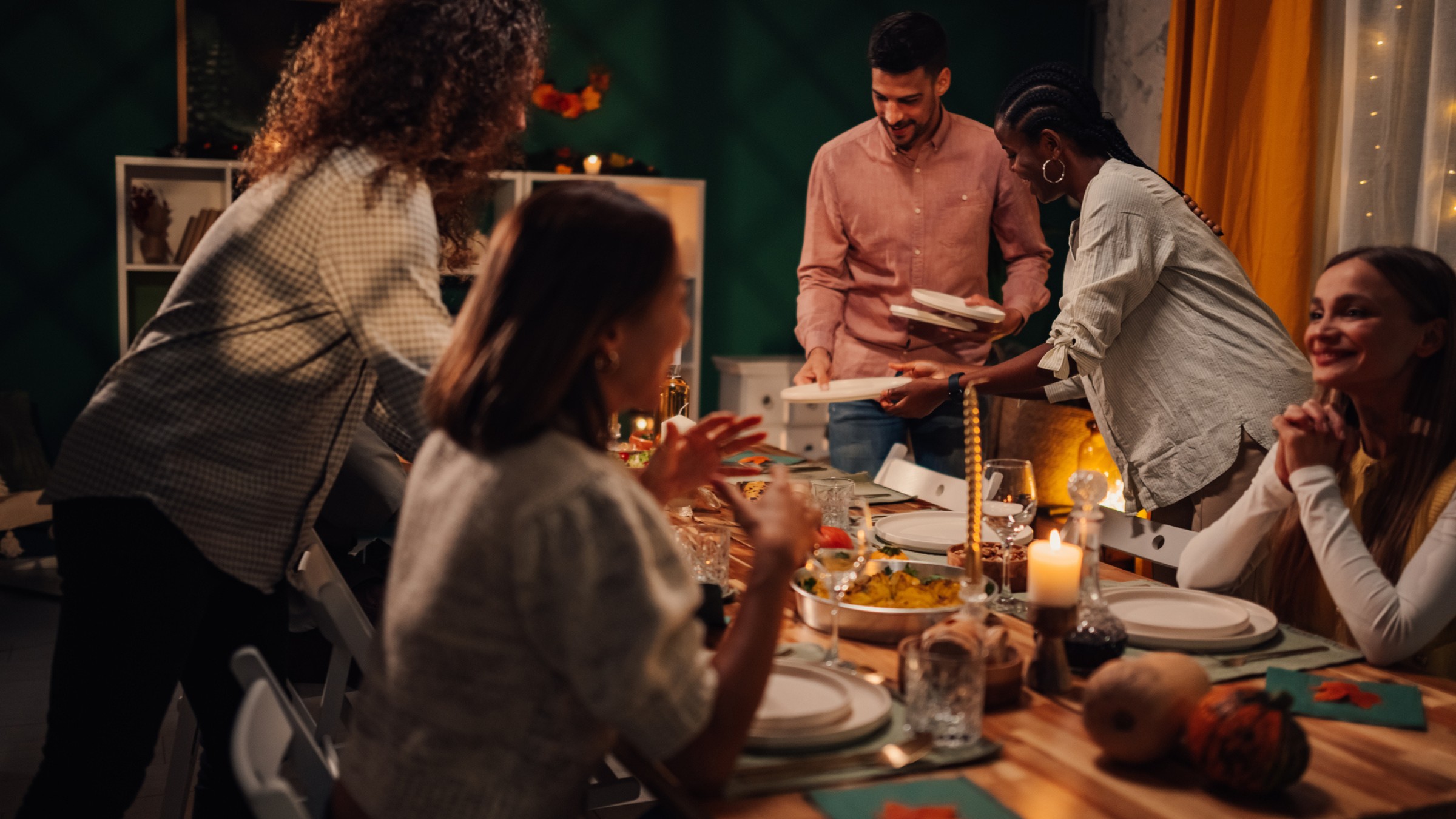 Friends gathered around a dinner table with food and candles