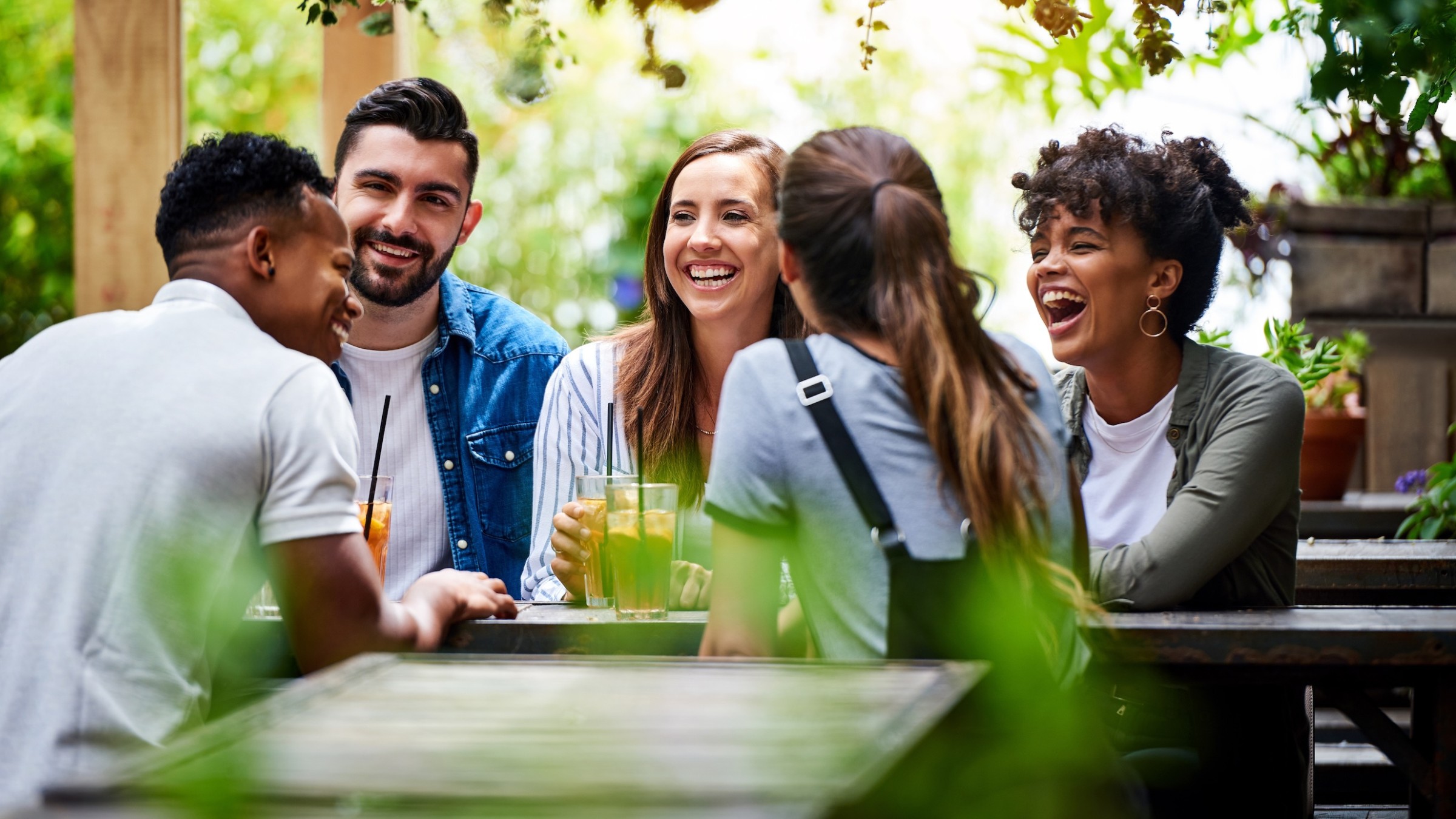 A diverse group of friends laughing around an outdoor patio table